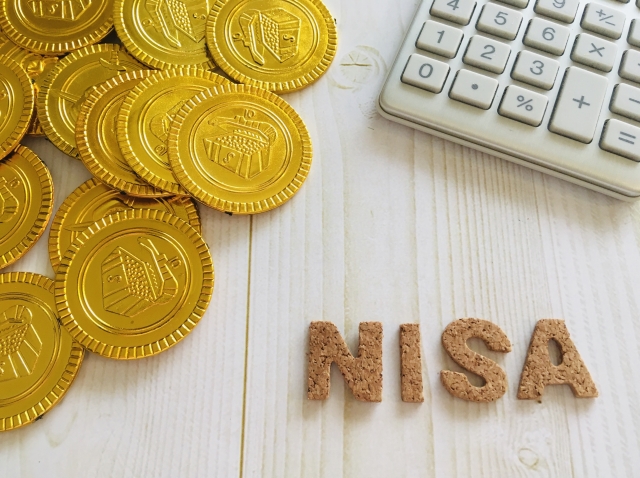 電卓とコインで資産計算をする様子 NISA投資と資産形成のイメージ